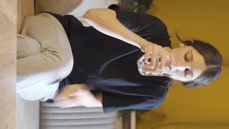 Vertical-video-of-Cowardly-young-woman-drinks-water-with-trembling-hand.